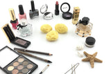Drei kleine Kosmetikschwämme aus Naturschwamm zwischen Lippenstiften, Nagellack, Lidschatten-Palette und Parfum