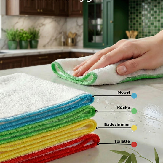 Gefaltete Bambus-Putztücher als Stapel mit Farblegende: Blau für Möbel, Grün für Küche, Gelb für Badezimmer, Rot für Toilette; eine Hand wischt die Arbeitsplatte