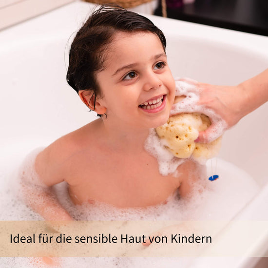 Kind beim Baden mit weichem Badeschwamm aus Naturmaterial – sanft zur empfindlichen Kinderhaut