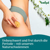 Frau hält einen kleinen Menstruationsschwamm an die Hüfte, dazu der Text „Unbeschwert und frei durch die Periode“